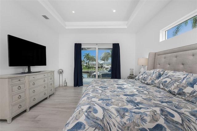 bedroom with a tray ceiling, access to outside, and light hardwood / wood-style flooring