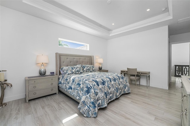 bedroom featuring light wood-type flooring and a raised ceiling