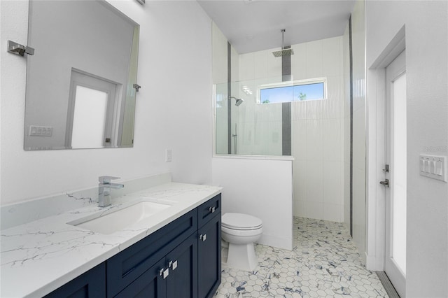 bathroom featuring vanity, toilet, tiled shower, and tile patterned flooring