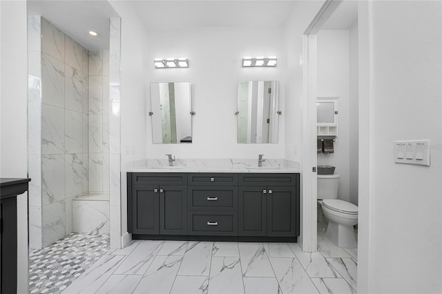 bathroom with toilet, a tile shower, and vanity