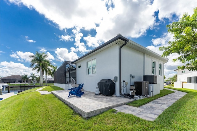 back of house with glass enclosure, a yard, a water view, and a patio area