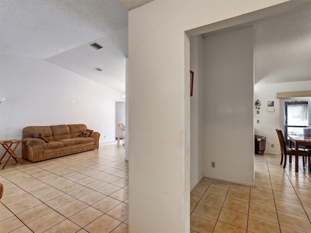 interior space featuring light tile patterned floors, a textured ceiling, and vaulted ceiling