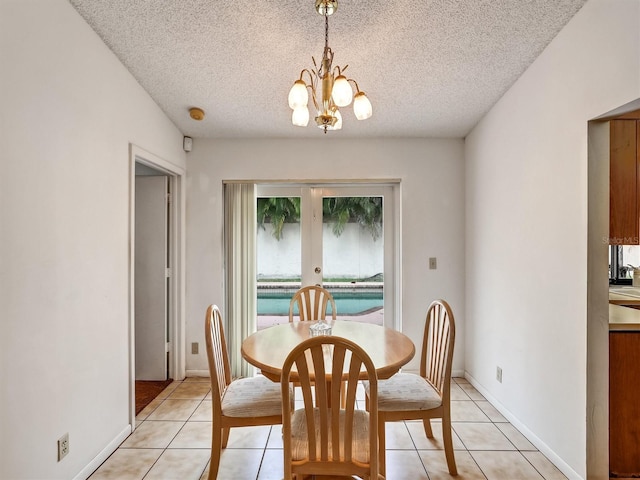 tiled dining space featuring a chandelier, french doors, and a textured ceiling