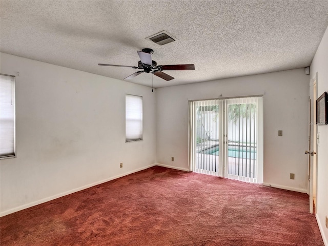 spare room with a textured ceiling, dark carpet, and ceiling fan