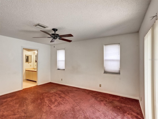 carpeted spare room with ceiling fan, plenty of natural light, and a textured ceiling