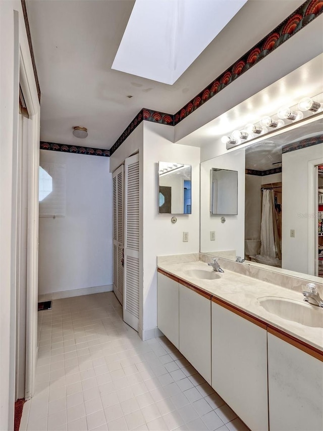 bathroom with tile patterned floors, a skylight, and vanity