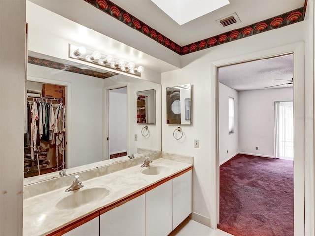 bathroom with ceiling fan, vanity, and a textured ceiling