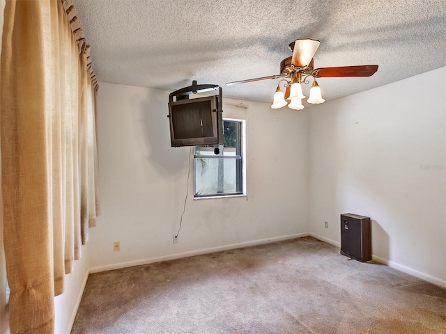 empty room featuring ceiling fan, carpet floors, and a textured ceiling