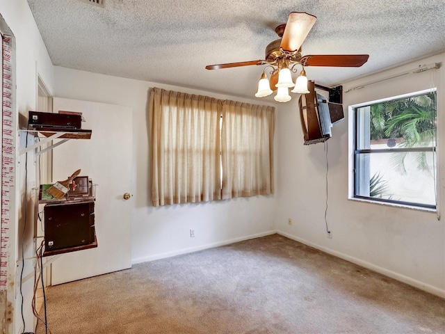 empty room featuring light carpet, ceiling fan, and a textured ceiling