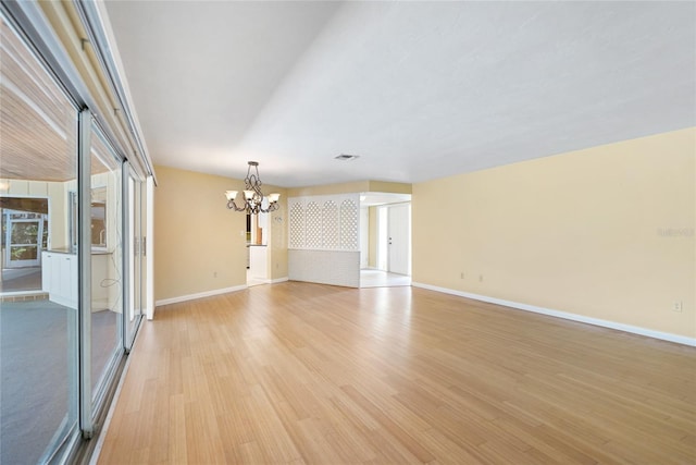 empty room featuring light hardwood / wood-style flooring and a notable chandelier