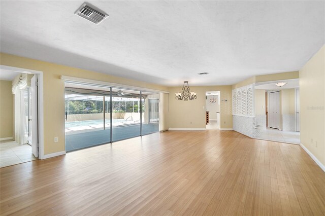 unfurnished living room featuring light hardwood / wood-style flooring and an inviting chandelier