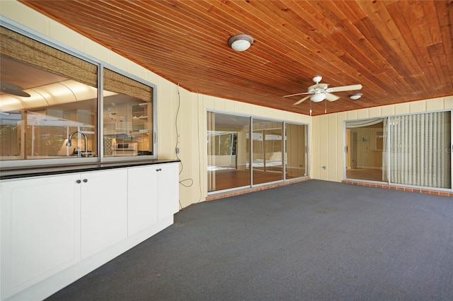 unfurnished sunroom with ceiling fan and wooden ceiling