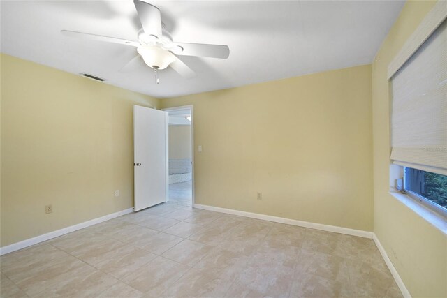 tiled spare room with ceiling fan