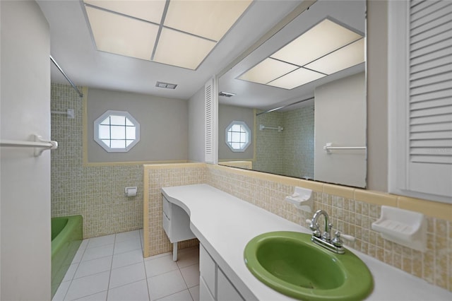 full bathroom with a wainscoted wall, tile walls, visible vents, vanity, and tile patterned flooring