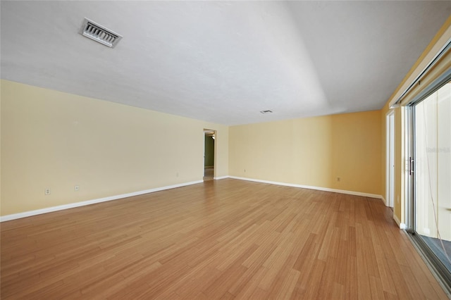 spare room with light wood finished floors, visible vents, and baseboards