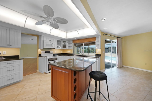 kitchen featuring a center island, light hardwood / wood-style flooring, white appliances, ceiling fan, and a kitchen breakfast bar