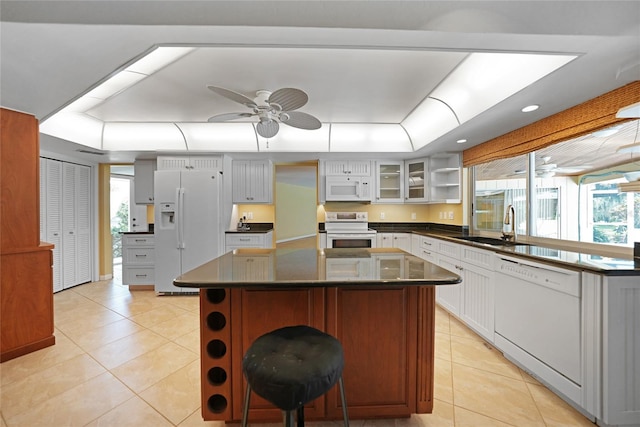 kitchen featuring glass insert cabinets, white appliances, white cabinets, and a kitchen island