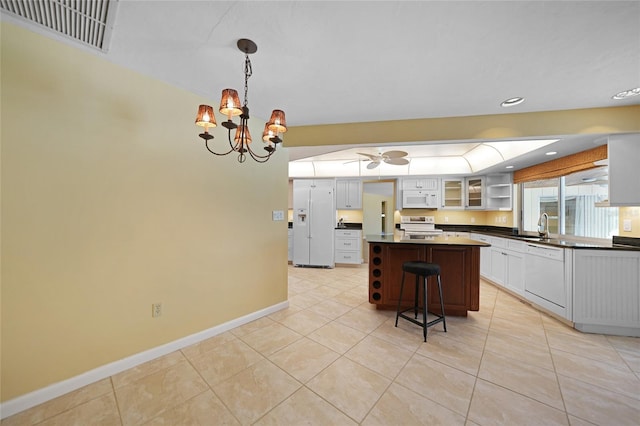 kitchen featuring white appliances, visible vents, glass insert cabinets, a center island, and white cabinetry