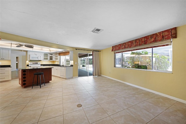 kitchen with visible vents, white microwave, glass insert cabinets, stainless steel range with electric cooktop, and a kitchen breakfast bar