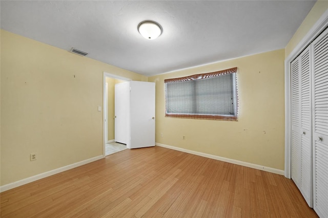 unfurnished bedroom with light wood finished floors, a closet, visible vents, and baseboards