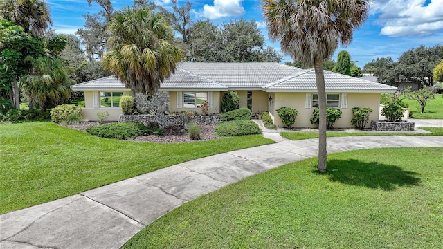 single story home featuring a tiled roof, a front lawn, and stucco siding