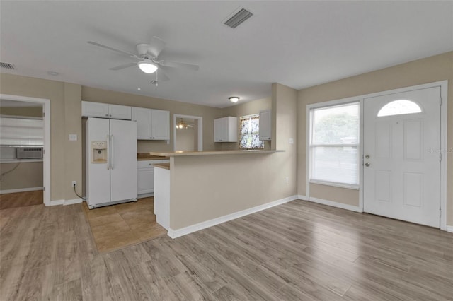 interior space featuring ceiling fan, kitchen peninsula, light hardwood / wood-style flooring, white cabinetry, and white fridge with ice dispenser