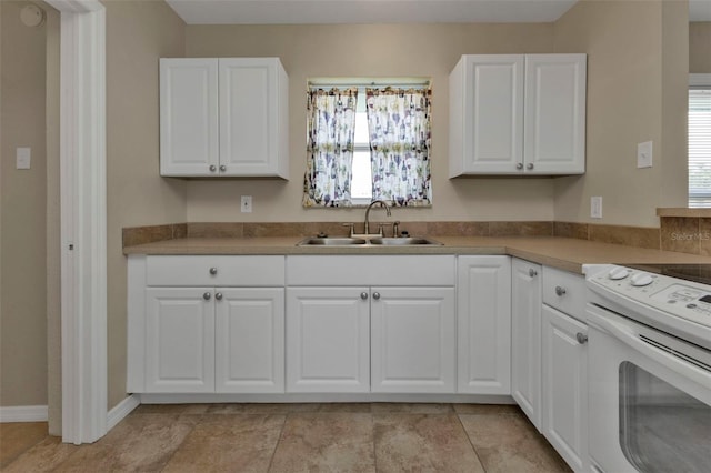 kitchen featuring white cabinets, light tile patterned flooring, white electric stove, and sink