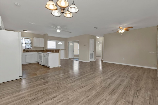 unfurnished living room featuring light wood-type flooring, ceiling fan with notable chandelier, and sink