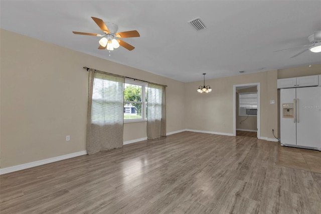 unfurnished living room with cooling unit, ceiling fan with notable chandelier, and light hardwood / wood-style floors