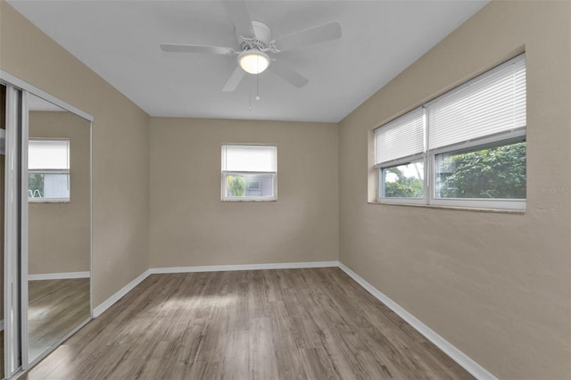 empty room with ceiling fan, light hardwood / wood-style floors, and a healthy amount of sunlight