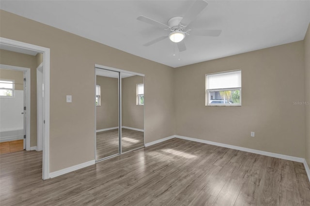 unfurnished bedroom featuring light wood-type flooring, ceiling fan, and a closet