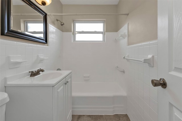 full bathroom with a wealth of natural light, tiled shower / bath, vanity, and toilet