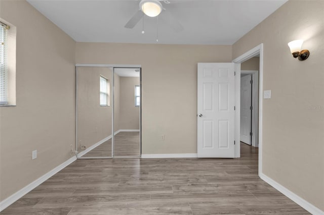 unfurnished bedroom with light wood-type flooring, a closet, and ceiling fan