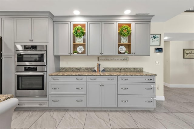 kitchen with stone counters, stainless steel double oven, and gray cabinets