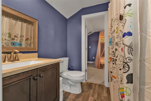 bathroom featuring hardwood / wood-style floors, vanity, toilet, and lofted ceiling