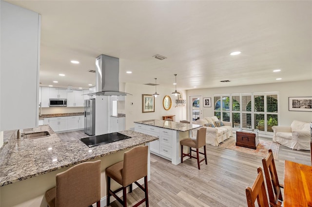 kitchen featuring island exhaust hood, stainless steel appliances, white cabinets, and a breakfast bar