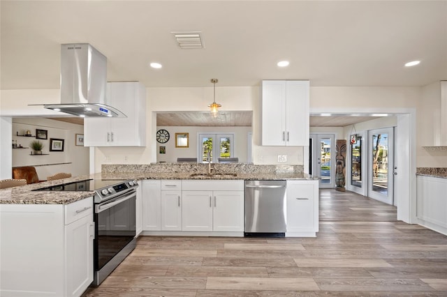 kitchen with appliances with stainless steel finishes, light stone counters, kitchen peninsula, and island range hood