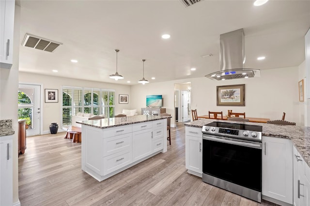 kitchen with island range hood, light stone counters, electric stove, light wood-type flooring, and white cabinets