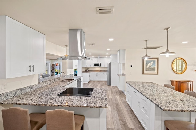 kitchen with appliances with stainless steel finishes, sink, island exhaust hood, kitchen peninsula, and a breakfast bar area