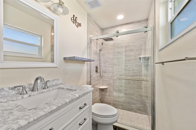 bathroom with vanity, a shower with shower door, and toilet