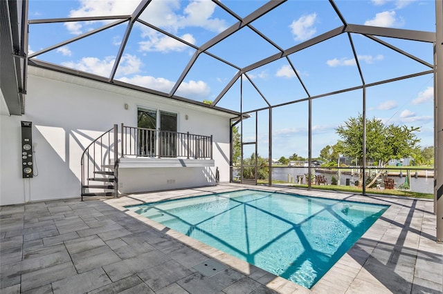 view of swimming pool featuring glass enclosure, a water view, and a patio