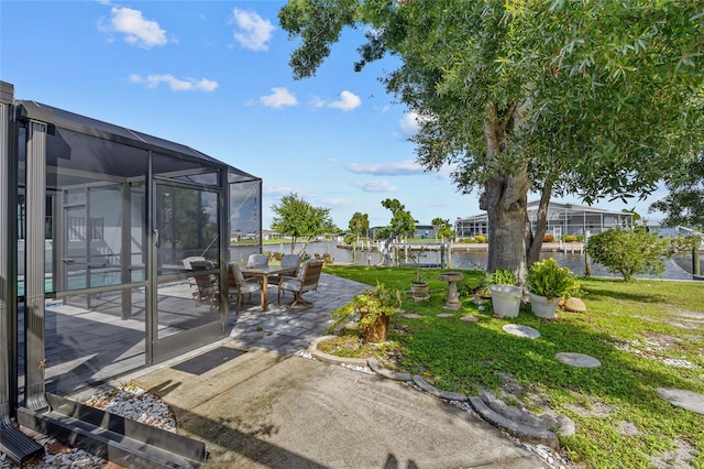 view of yard with a lanai, a patio area, and a water view