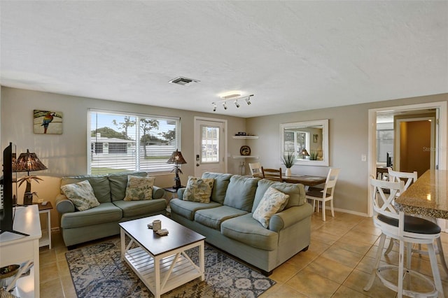 living room with a textured ceiling and light tile patterned flooring