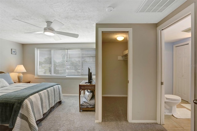 bedroom with carpet, ceiling fan, ensuite bath, and a textured ceiling