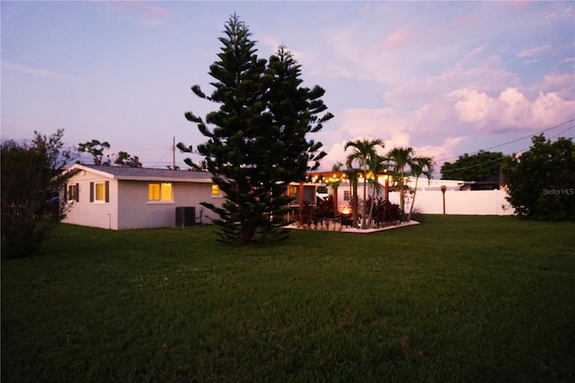 yard at dusk with a patio and central AC