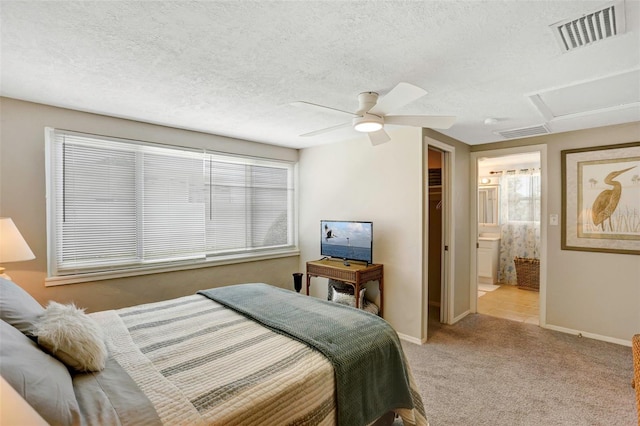 carpeted bedroom with a textured ceiling, ensuite bath, ceiling fan, and a closet