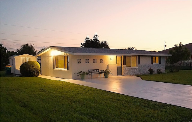 view of front of home featuring a storage shed, a patio area, and a yard