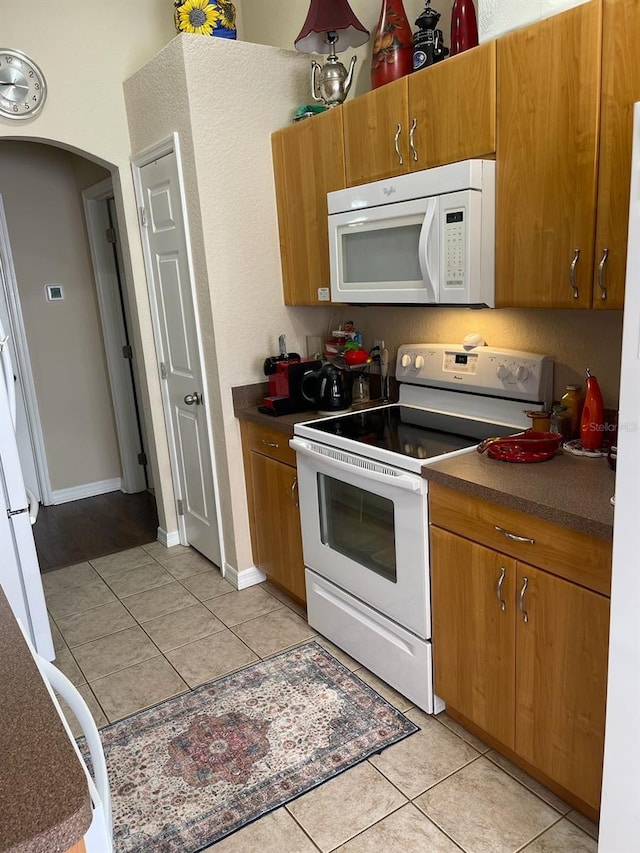 2106 Switzerland Rd, North Port, FL 34288 - kitchen with white appliances, light tile patterned floors, dark countertops, and arched walkways