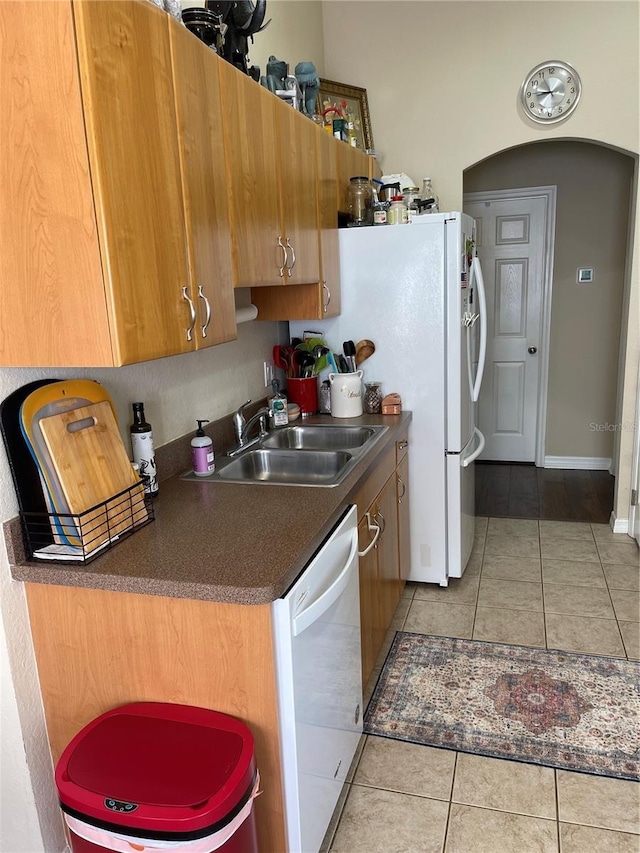 2106 Switzerland Rd, North Port, FL 34288 - kitchen featuring a sink, dishwasher, dark countertops, light tile patterned flooring, and brown cabinets