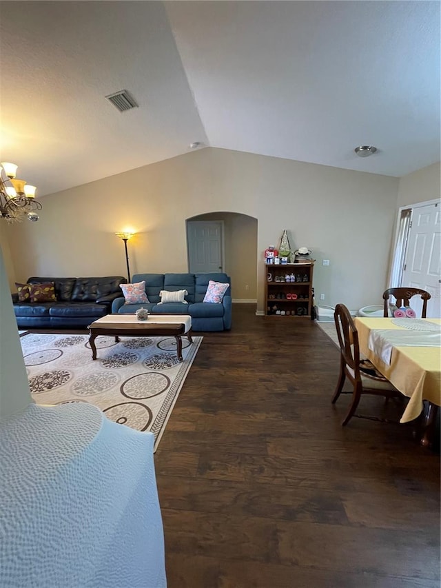 living room featuring dark wood-type flooring, lofted ceiling, and a notable chandelier